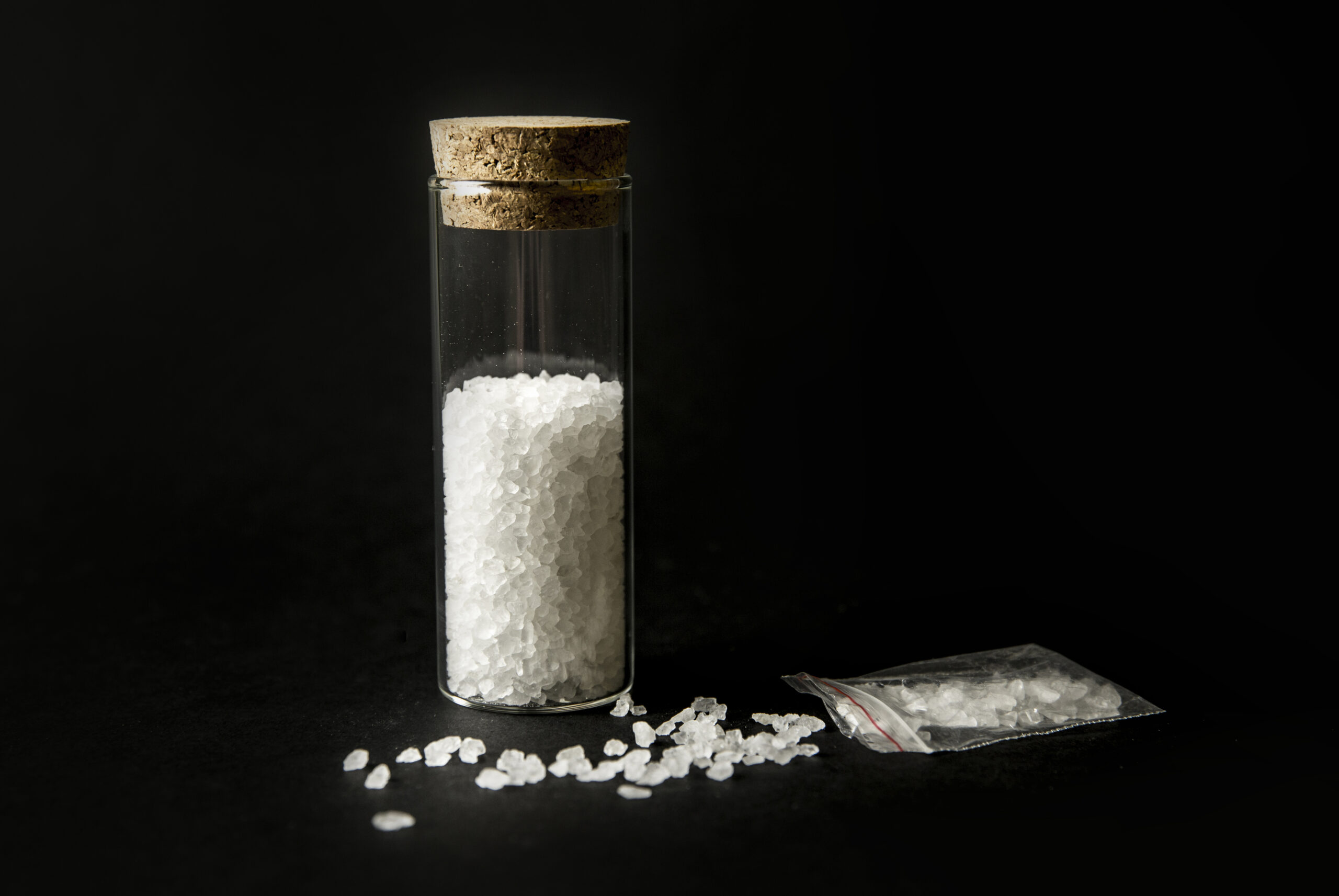 Conceptual image of "bath salts" synthetic cathinones drugs narcotics concept. White crystal powder on black background( set up), resemble to bathroom bath salt. Badesalz drogen online bestellen